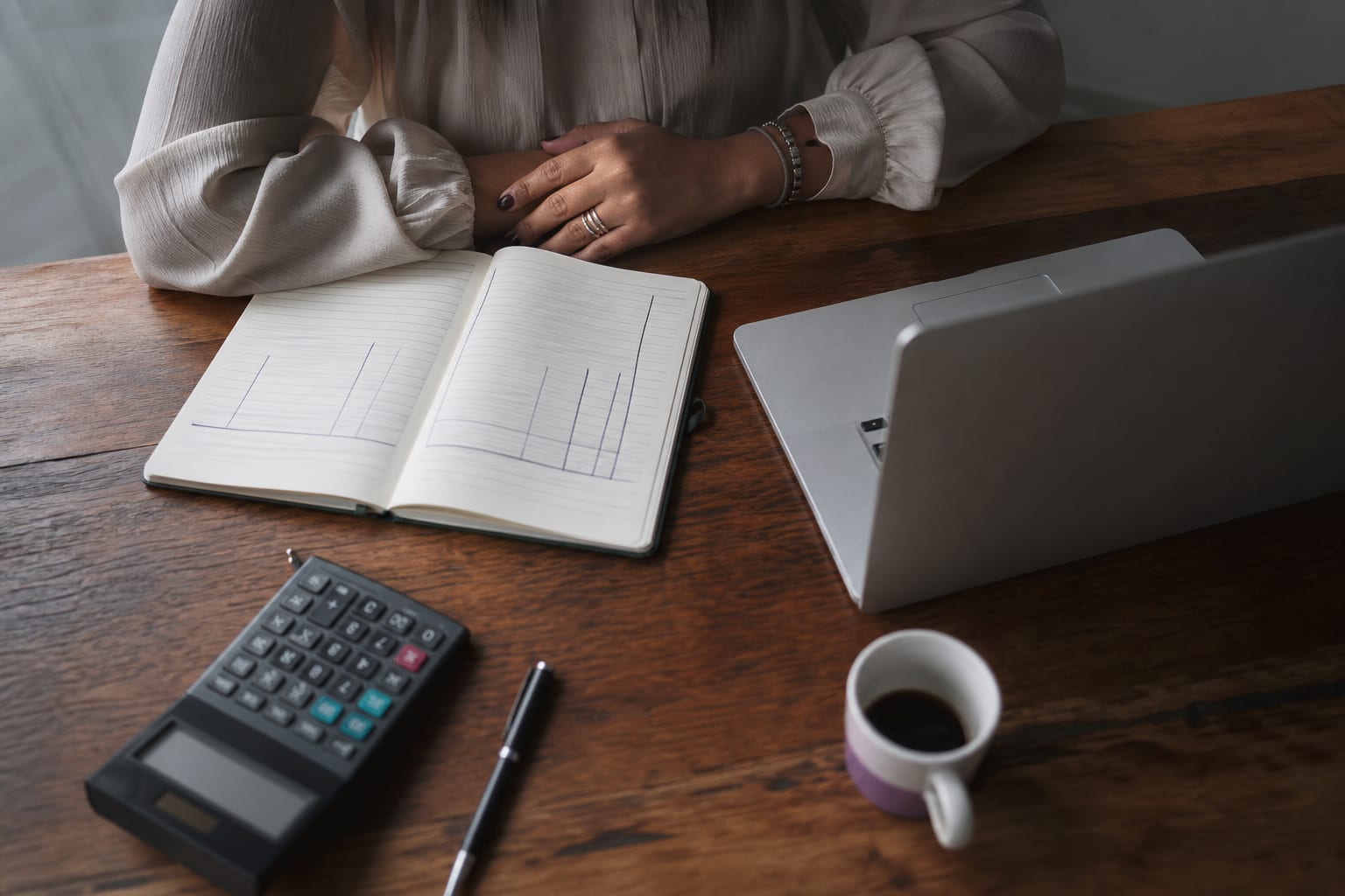 Mesa de trabalho com calculadora, caderno e notebook durante o fechamento de um orçamento
